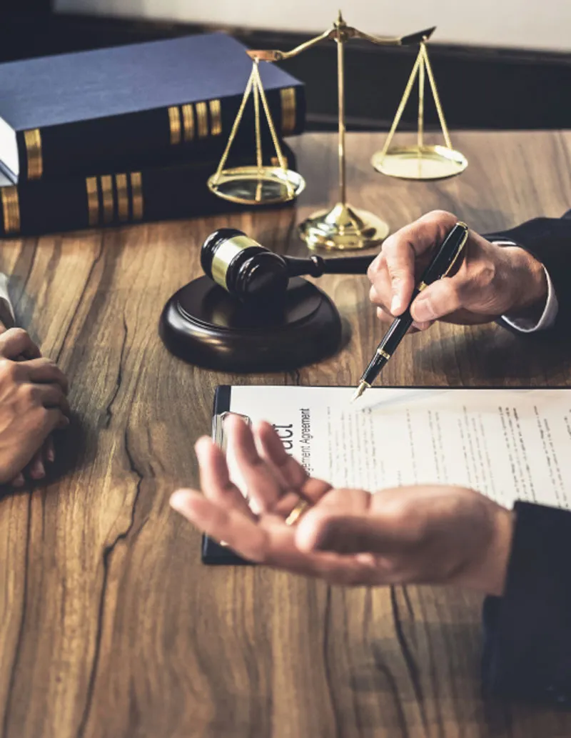 A lawyer reviewing an agreement with a client beside a gavel and scales